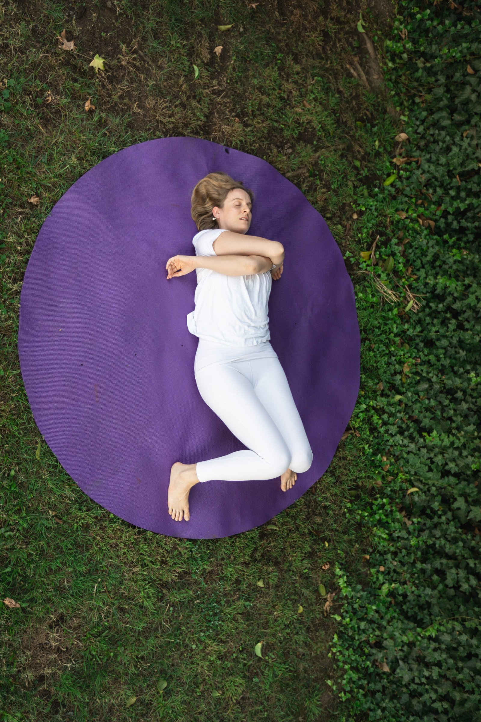Charlotte lying on a purple mat stretching